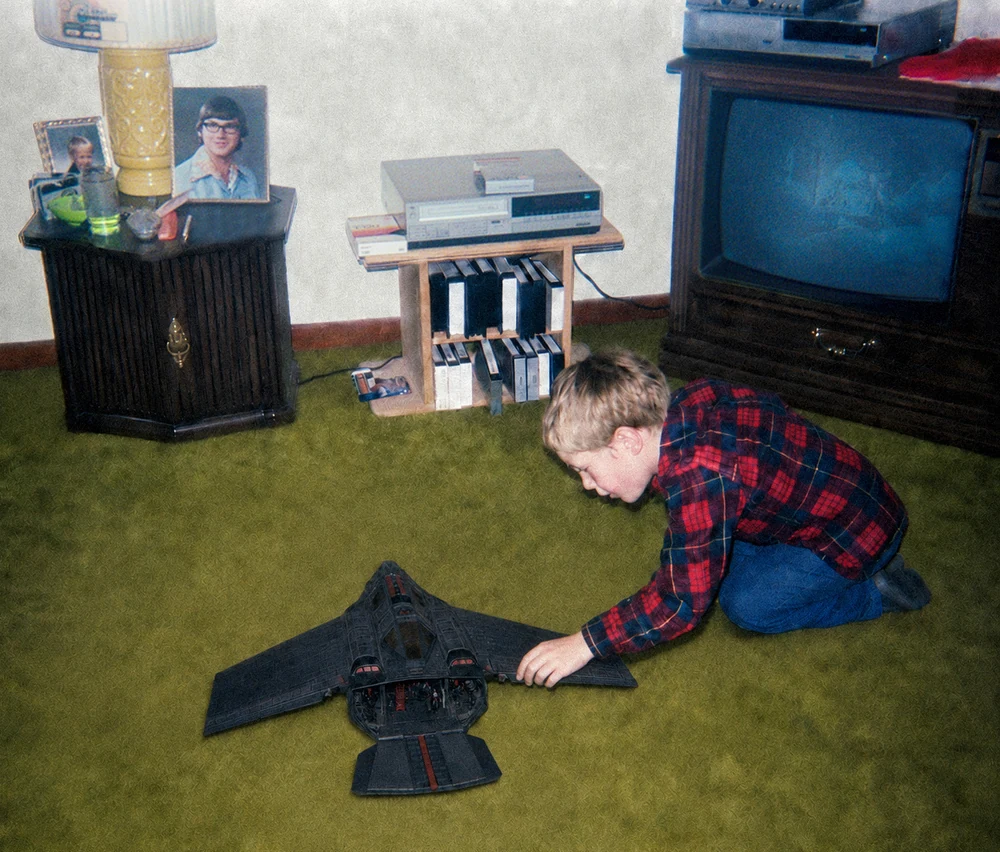 A child playing with a Shadow Wing toy on a living room floor.